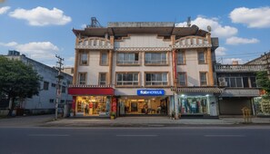 Un edificio a più piani con un'insegna 'fabHOTELS', negozi al piano terra e cielo sereno.