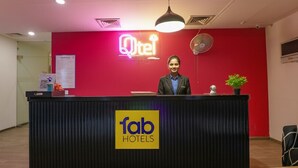 Ein Hotelrezeptionstresen mit einem Neon-Schild für 'Qtel' und dem Logo 'fab hotels'.