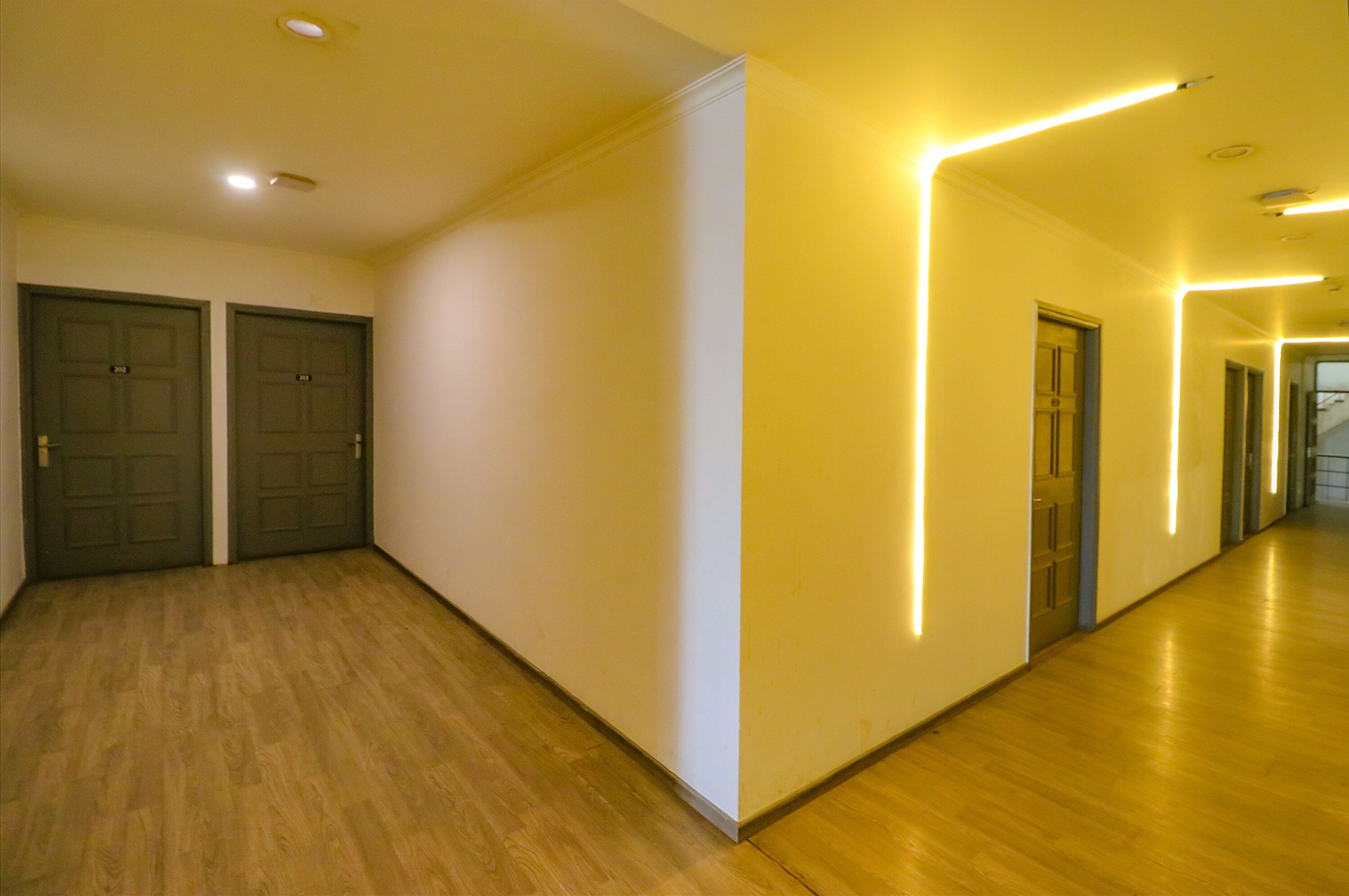 Pasillo con suelo y paredes de madera, con dos puertas y paneles de pared iluminados.