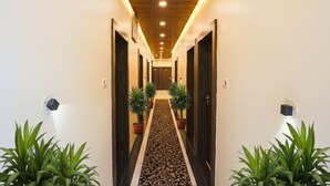 Un pasillo con alfombra estampada, plantas en macetas y puertas de madera.