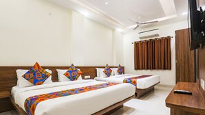 Habitación de hotel con dos camas, cabecero de madera, televisor de pantalla plana y ventilador de techo.