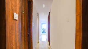 Un pasillo con puertas de madera y suelo de mármol, que conduce a una habitación luminosa con vistas.