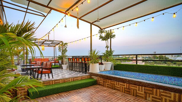 Un patio exterior con suelo de madera, mobiliario y una pequeña piscina.