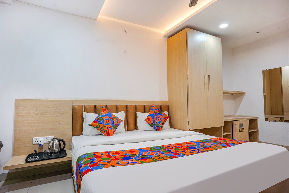 A hotel room with a bed, a nightstand, a coffee maker, and a wardrobe.