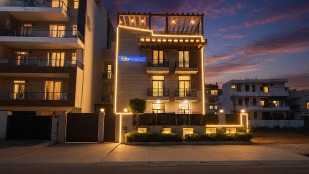 A modern building with multiple balconies and a well-lit entrance. - FabHotel JDM Residency (Gurugram)