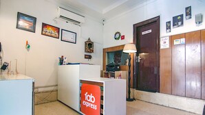 A reception area with a 'fab express' sign, a 'staff only' door, and various wall decorations including framed pictures and a clock. - FabHotel JDM Residency (Gurugram)