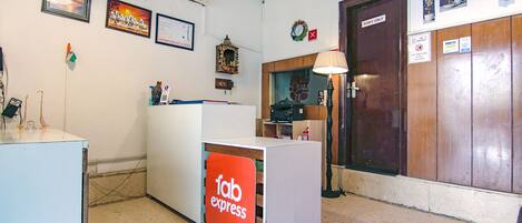 Un área de recepción con un letrero que dice 'fab express', una puerta para 'personal autorizado' y varias decoraciones en la pared, incluyendo cuadros y un reloj.