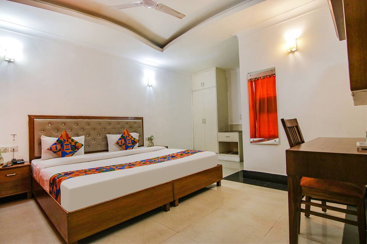 A bedroom with a bed, nightstand, wardrobe, and a dining area with a table and chairs.