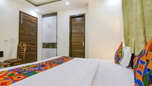 Una habitación de hotel con una cama grande, dos puertas de madera, una silla y una mesita.