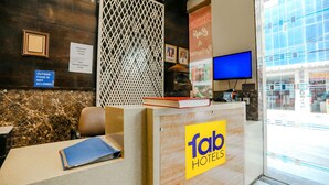A hotel reception desk with a 'fab hotels' sign, a computer monitor, and a view of the outside. - Fabhotel Station I (New Delhi)