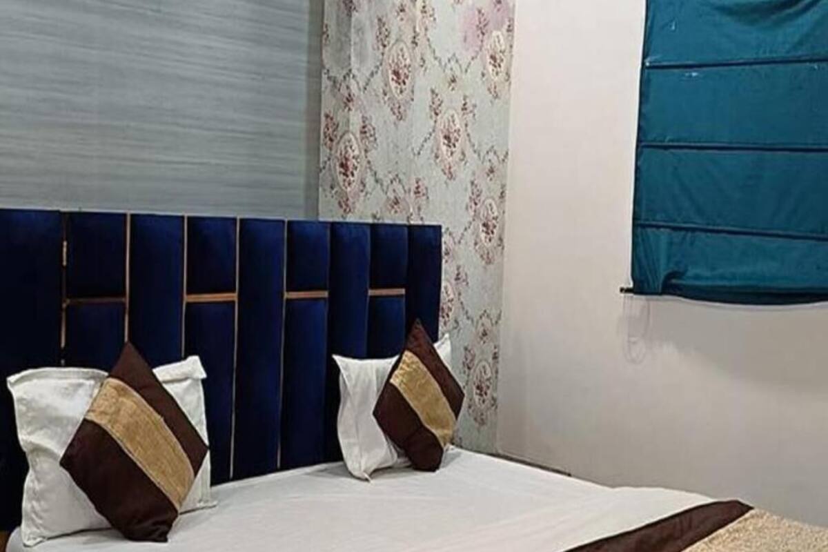 Ein Bett mit blauem Kopfteil, weißer Bettwäsche und Zierkissen.