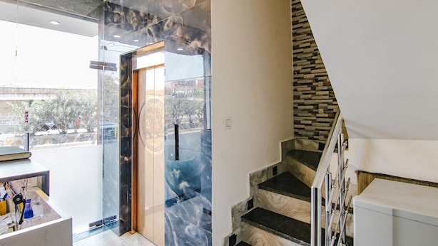 A modern interior with a glass door leading to a balcony, a staircase with a stone accent wall, and a desk with office supplies. - Fabhotel Yellow Leaf (Ludhiana)