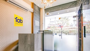 A hotel reception area with a 'Tab Hotels' sign, a modern reception desk, and a view of the street outside. - Fabhotel Yellow Leaf (Ludhiana)