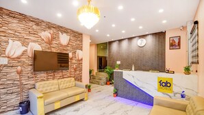 A hotel reception area with a marble floor, a reception desk, a sofa, and a chandelier. - Fabhotel Aqua Tulip (Kolkata)