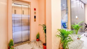 An elevator with a modern design, potted plants, and a marble floor. - Fabhotel Aqua Tulip (Kolkata)