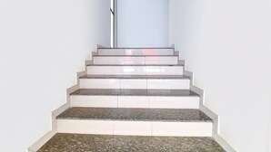 A staircase with a light-colored wall and a dark floor. - Fabhotel Infinity (Vadodara)