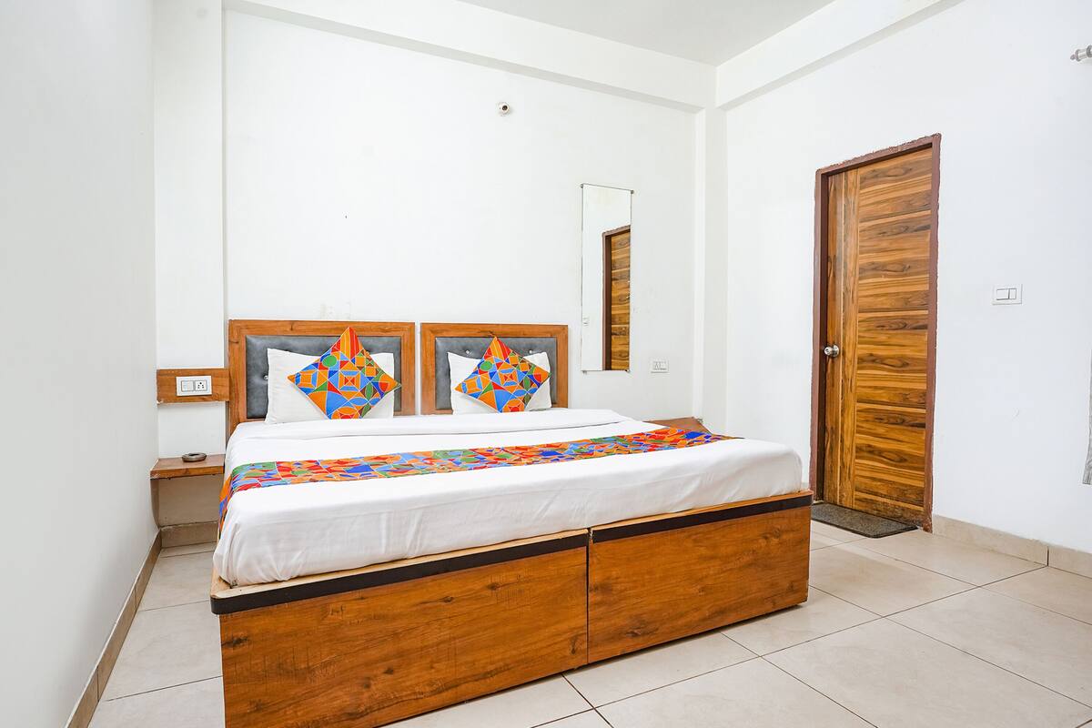 Un dormitorio con cama de madera, paredes blancas y una puerta de madera.