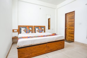 A bedroom with a wooden bed, white walls, and a wooden door.