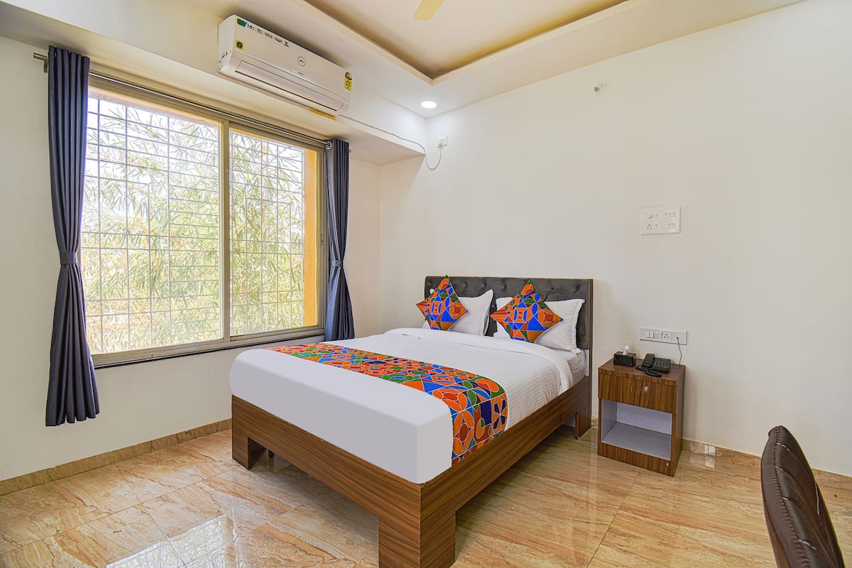 A bedroom with a bed, a nightstand, and a window with curtains.