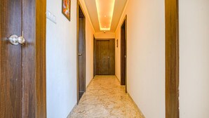 A narrow hallway with wooden doors, a marble floor, and recessed ceiling lighting. - Fabhotel Desire (Indore)