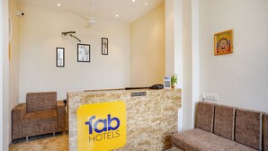 A reception area with a marble counter, framed artwork on the walls, and a ceiling fan. - Fabhotel Desire (Indore)