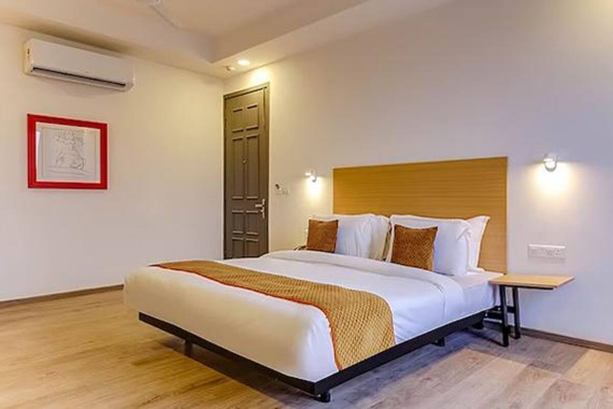 A hotel room with a large bed, wooden headboard, bedside tables, and a framed picture on the wall.
