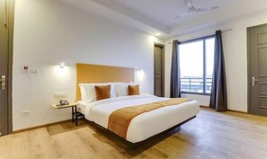 A hotel room with a large bed, a nightstand, a ceiling fan, and a window with curtains.