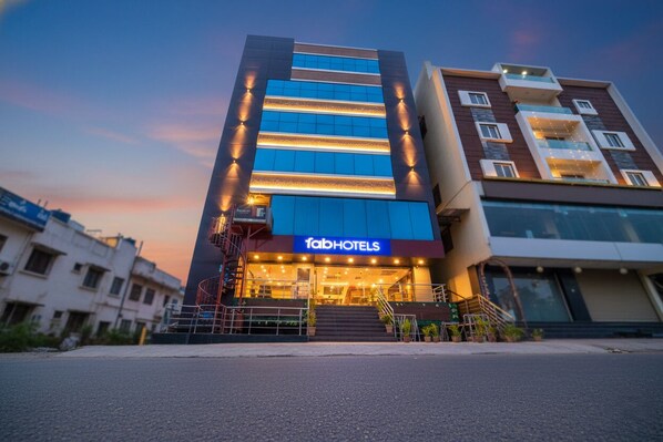 Et hotel i flere etager med en moderne facade, et tydeligt fabHOTELS skilt og en trappe, der fører til indgangen.