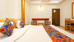 A hotel room with a bed, a desk, two chairs, and a door. - Fabhotel Clark Height (New Delhi)