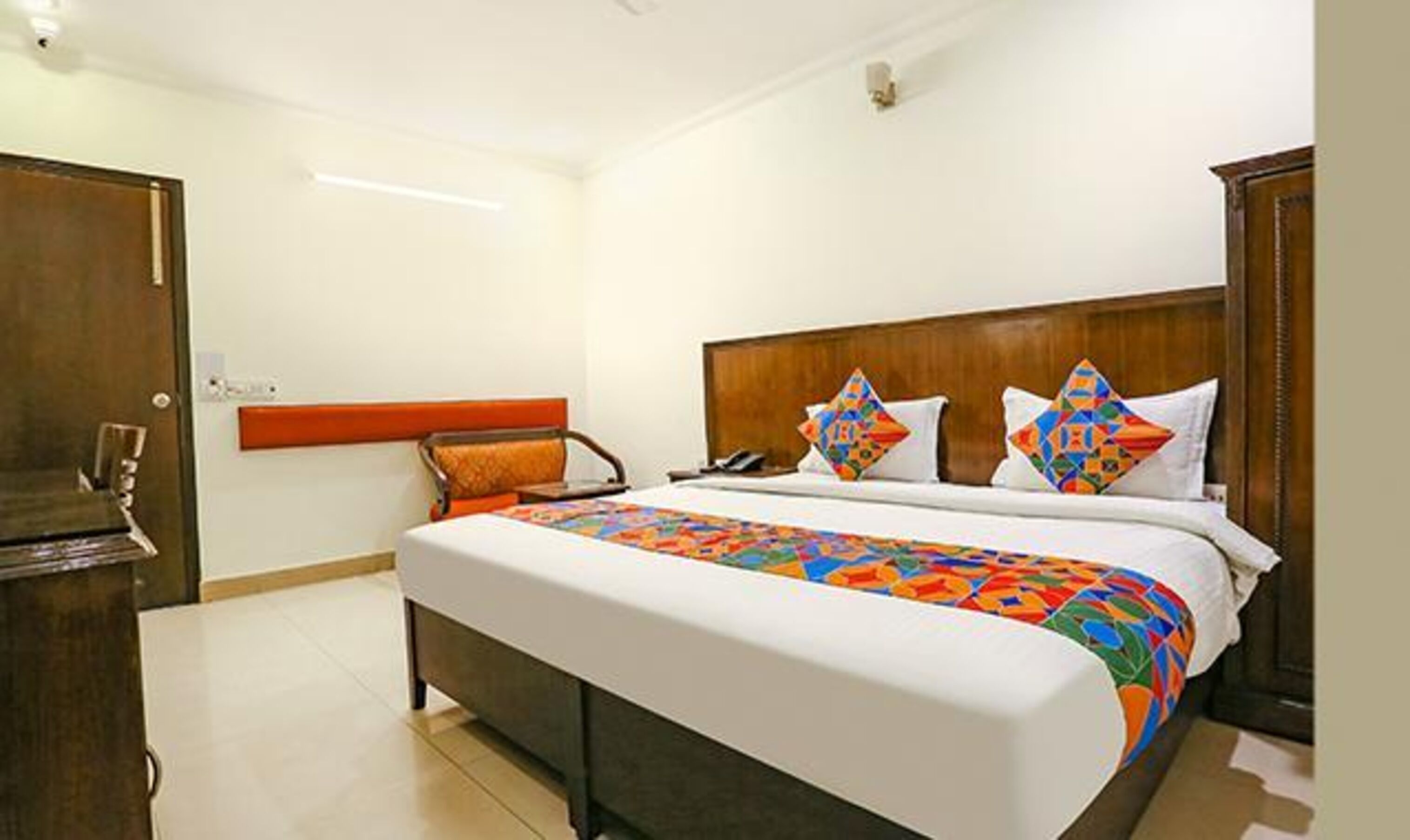 A hotel room with a large bed, a wooden headboard, and a nightstand.