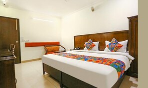 A hotel room with a large bed, a wooden headboard, and a nightstand. - FabHotel Clark Heights (New Delhi)
