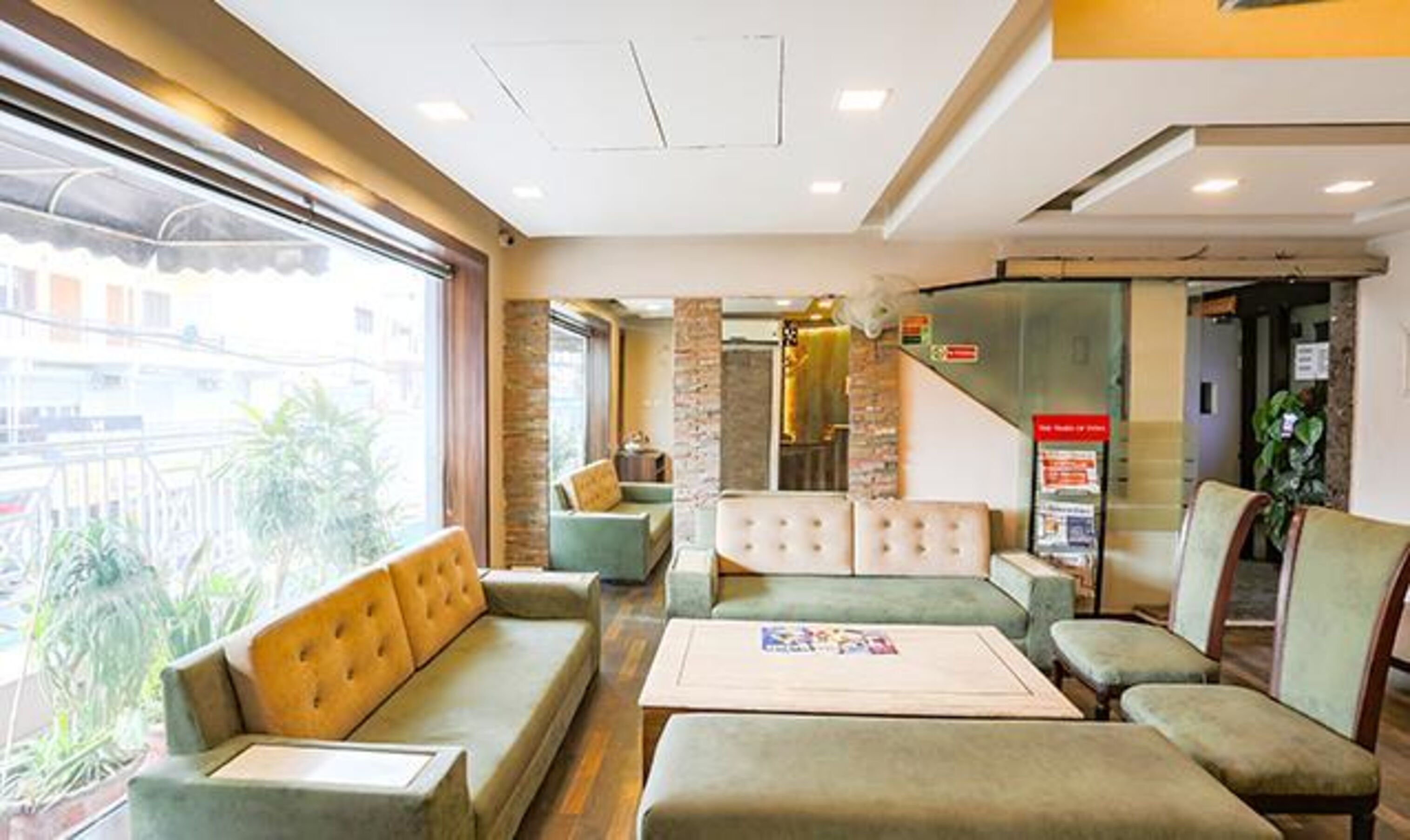 A hotel lobby with seating areas, a reception desk, and a staircase.