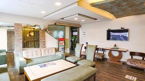 A lobby with a seating area, a staircase, and a TV mounted on the wall. - Fabhotel Clark Height (New Delhi)