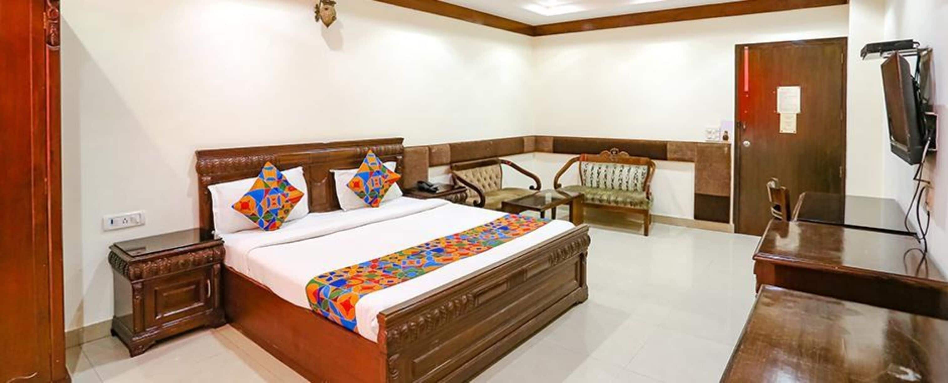 A hotel room with a large bed, a desk, a chair, and a television.