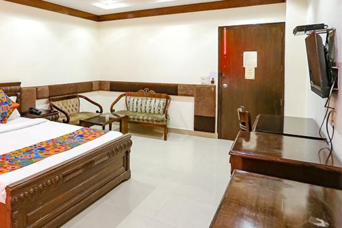 A hotel room with a large bed, a desk, a chair, and a television.
