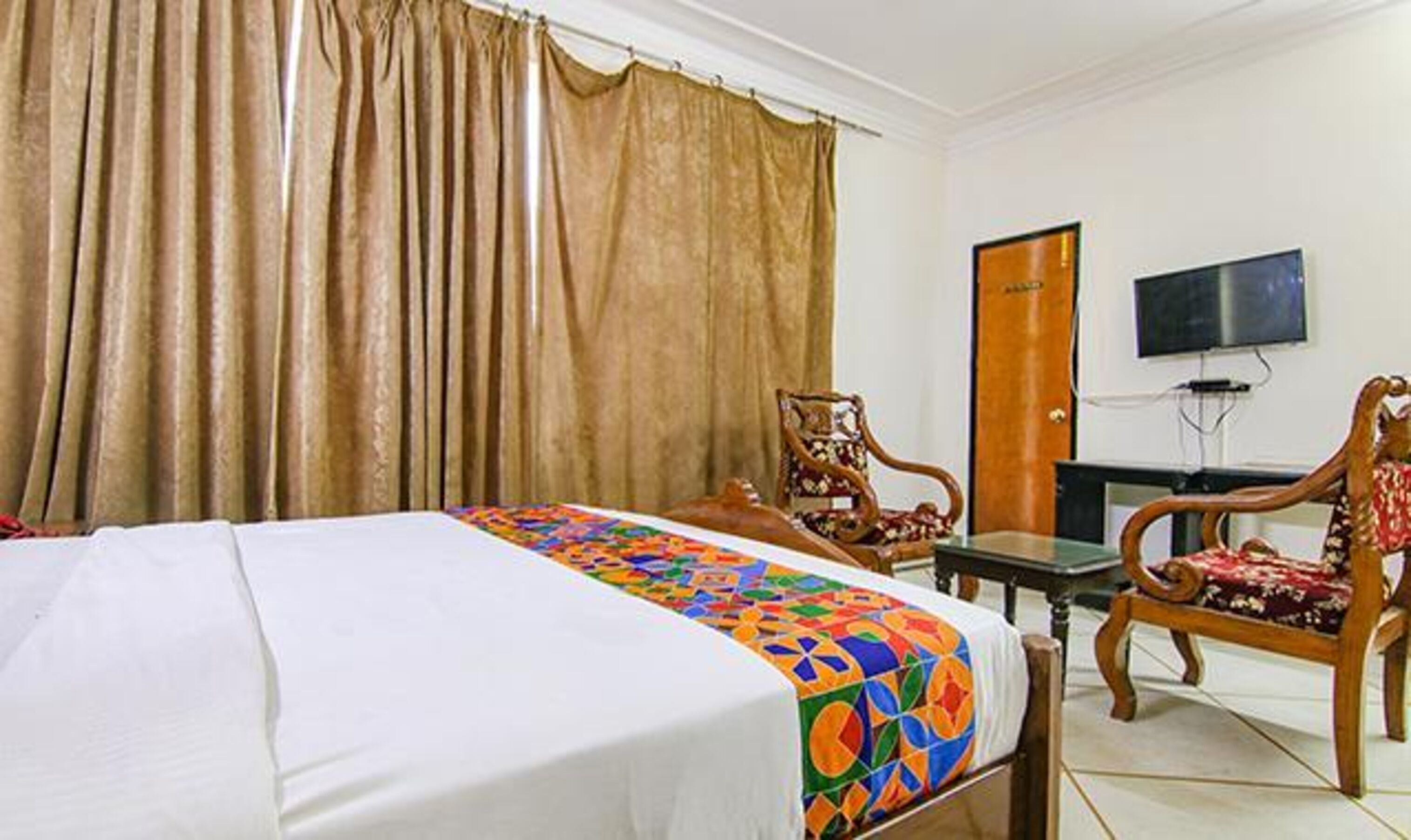 A hotel room with a bed, a desk, a chair, and a TV.