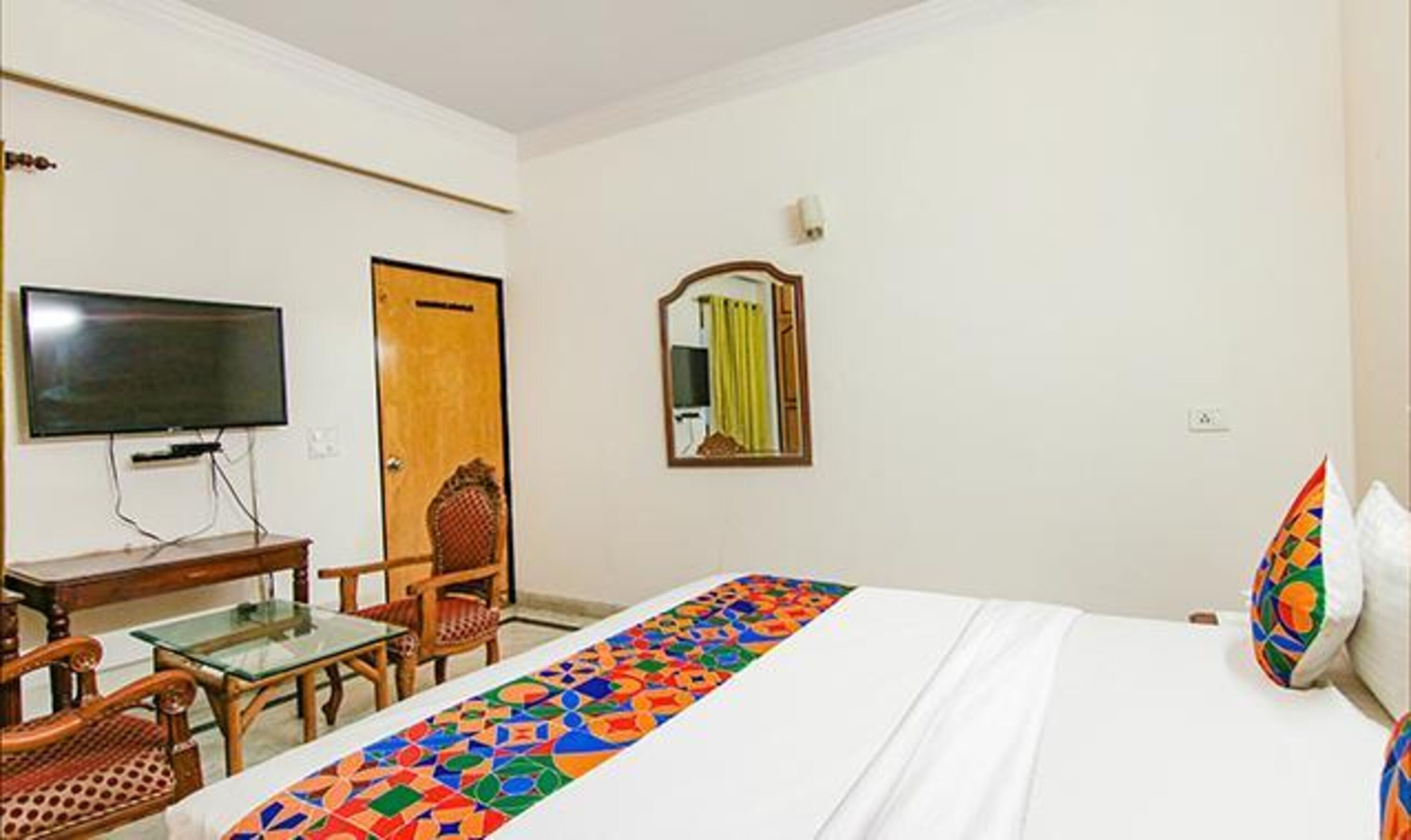 A hotel room with a bed, a TV, a desk, and a chair.