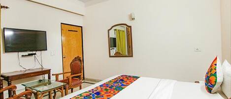 A hotel room with a bed, a TV, a desk, and a chair.