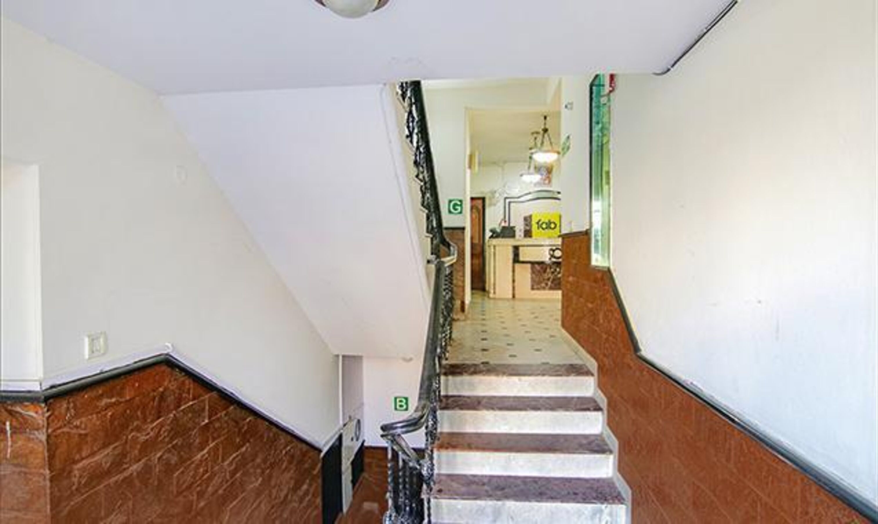A staircase with a marble floor and a metal railing.