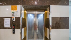 En elevator med digitalt display, kontaktinformation i nødstilfælde og en brandalarmkontakt.