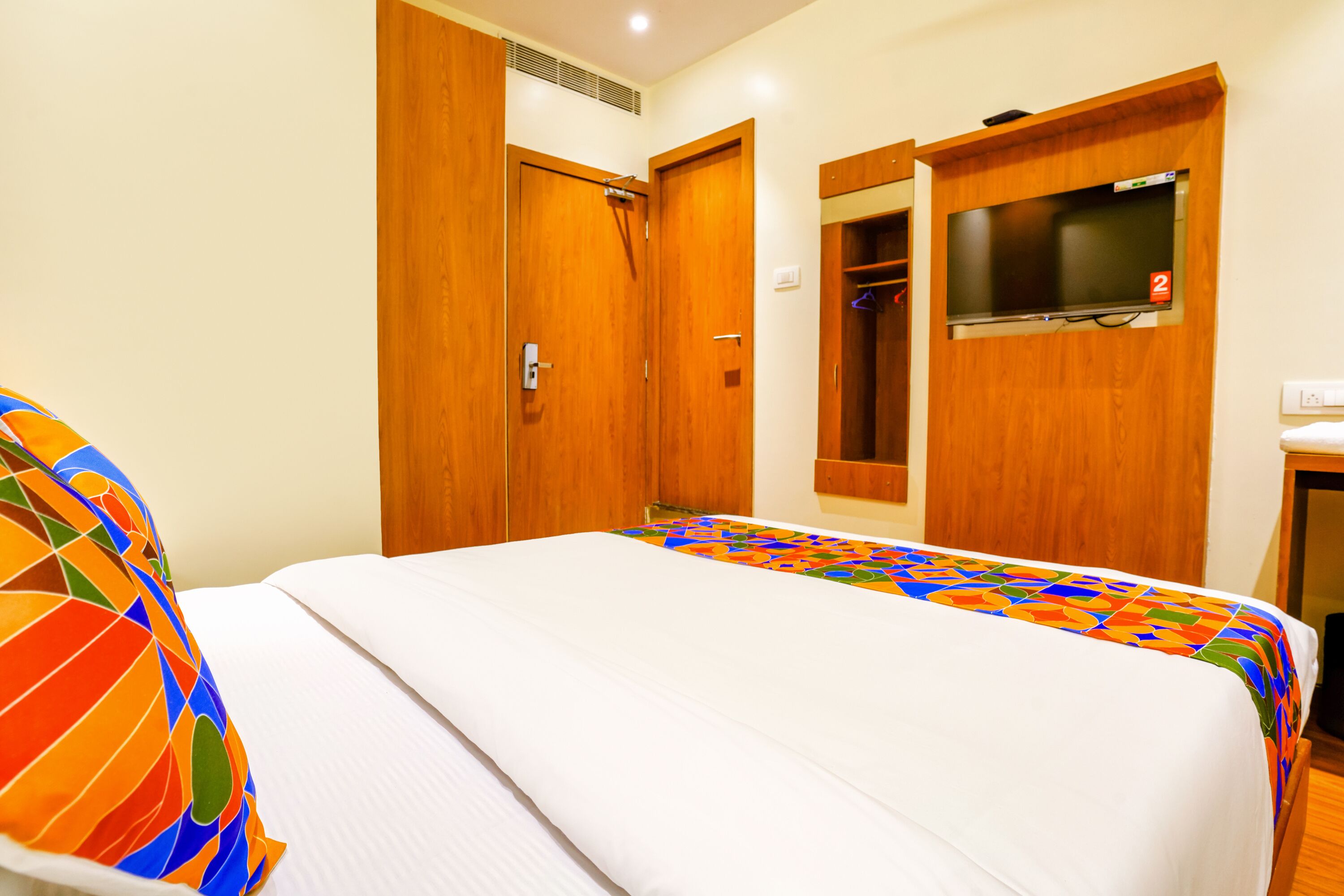 A hotel room with a bed, a wardrobe, and a television mounted on the wall.