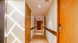 A hotel hallway with wooden floors, beige walls, and doors with a geometric pattern. - Fabhotel Azure (Mumbai)