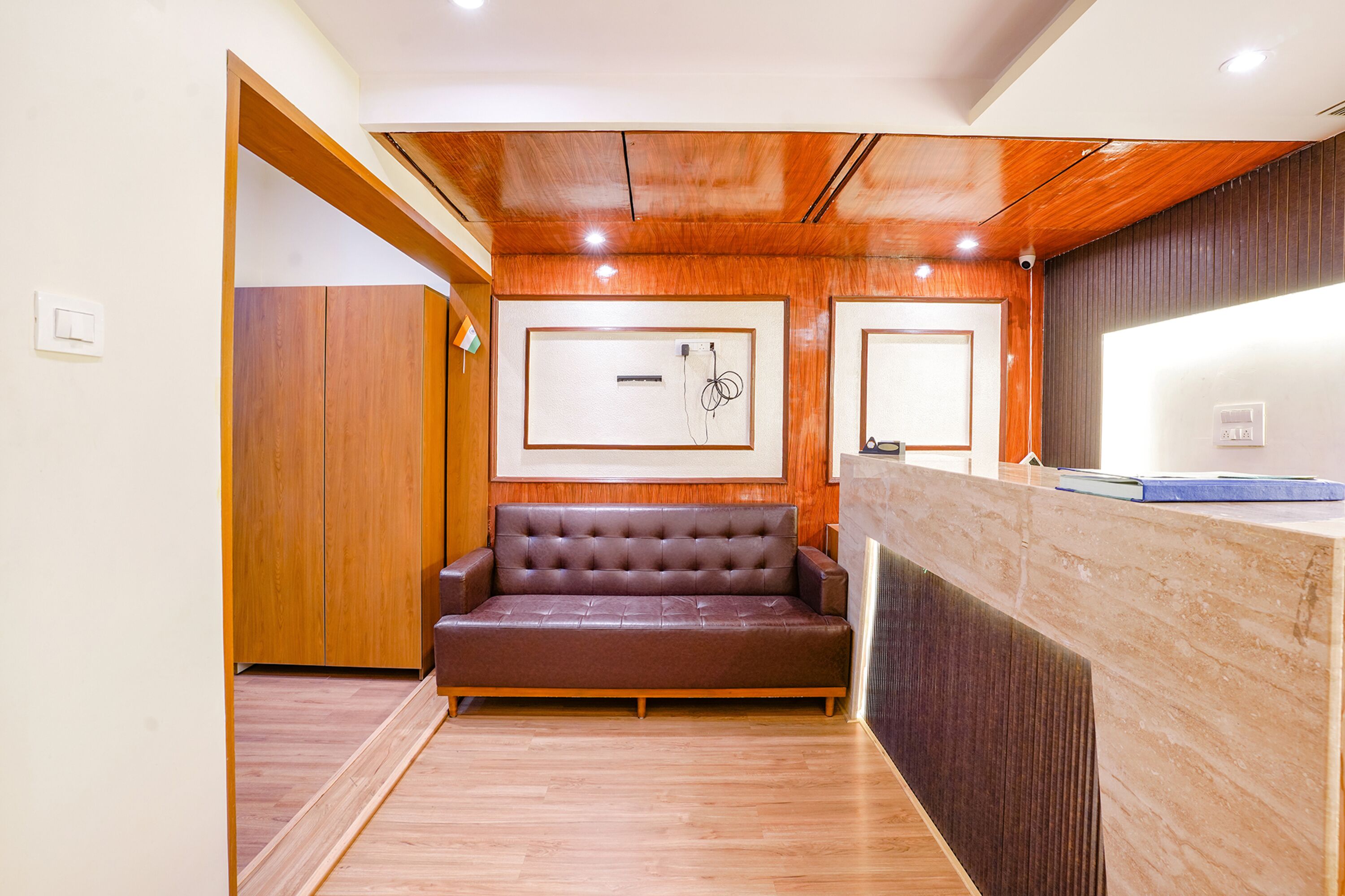 A reception area with a wooden reception desk, a brown leather sofa, and framed artwork on the wall.
