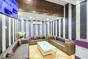 Una sala de estar moderna con paredes a rayas, sofás de cuero, una mesa de centro de vidrio y un televisor de pantalla plana montado en la pared.