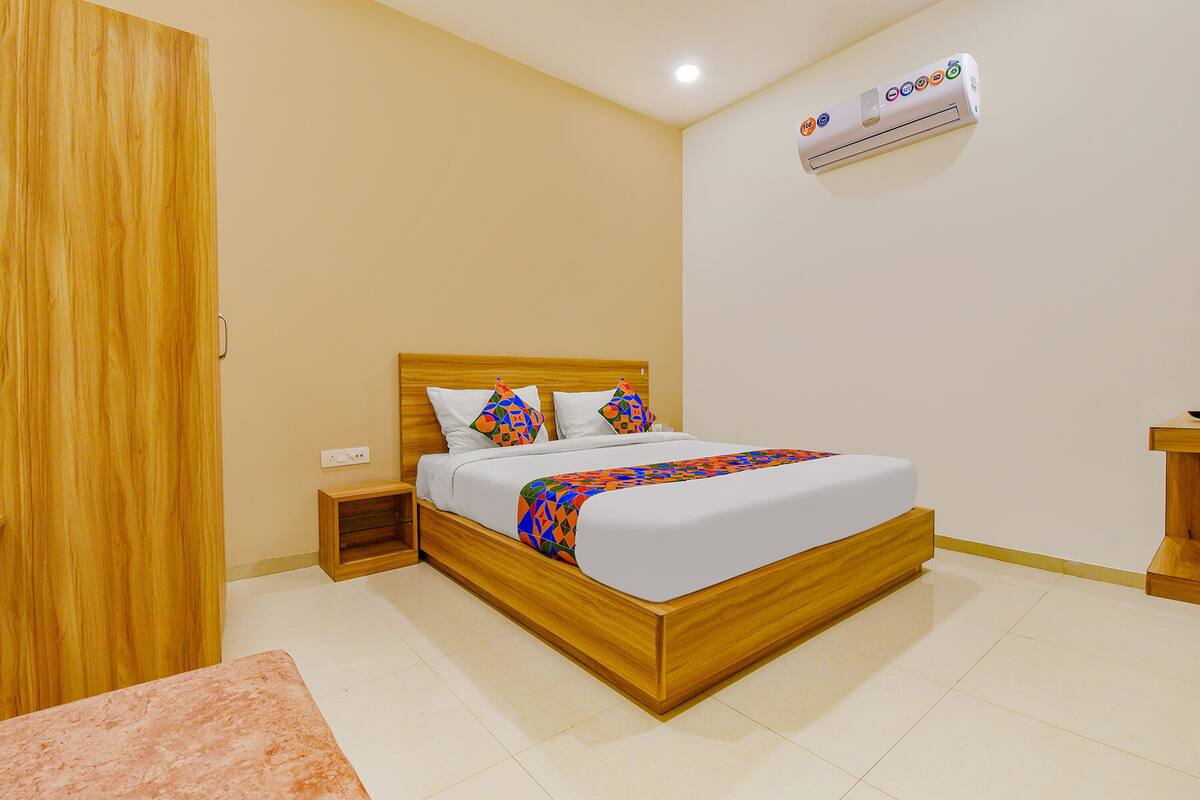 A bedroom with a wooden bed, white bedding, and a colorful throw blanket.
