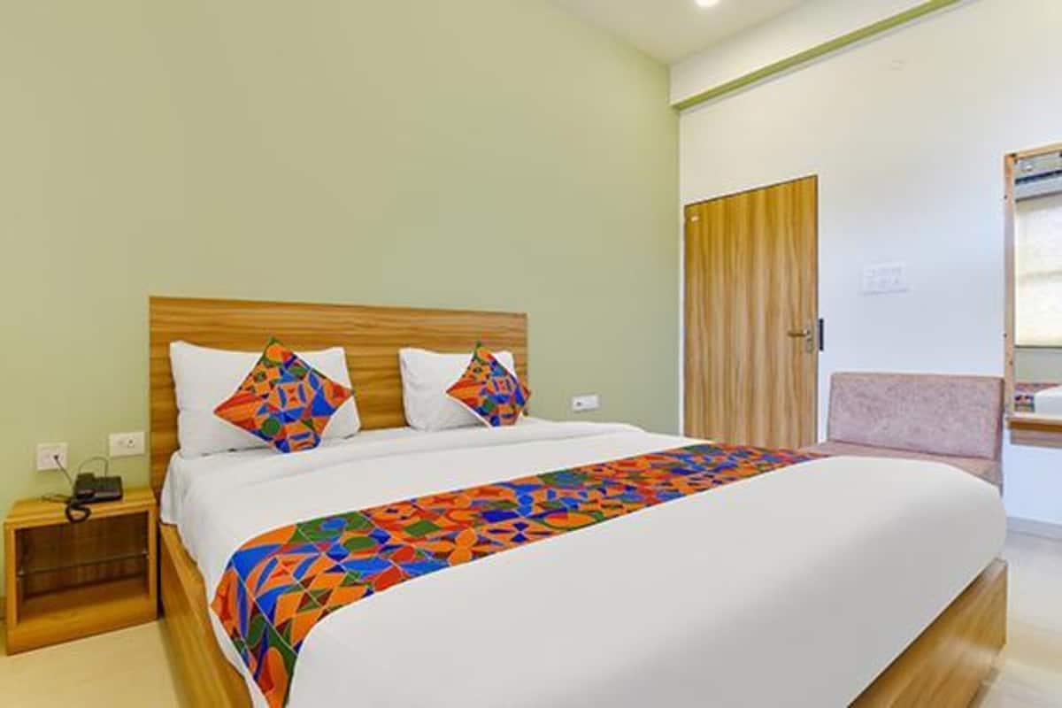 A hotel room with a bed, a nightstand, a wooden wardrobe, and a window.