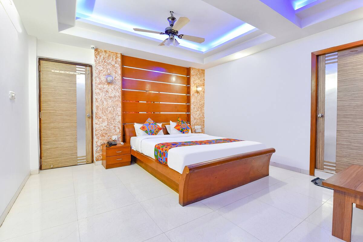 Une chambre moderne avec un lit en bois, une table de chevet, un ventilateur de plafond et une porte en bois.