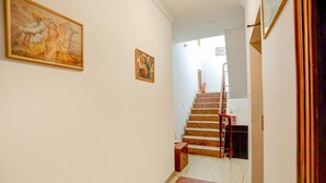 Un pasillo con una escalera que conduce a una plataforma. Hay dos obras de arte enmarcadas en las paredes.