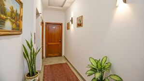 Un pasillo con una puerta de madera, una planta en maceta y un cuadro en la pared.