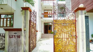 Una entrada protegida por un portón decorativo y un letrero con número.